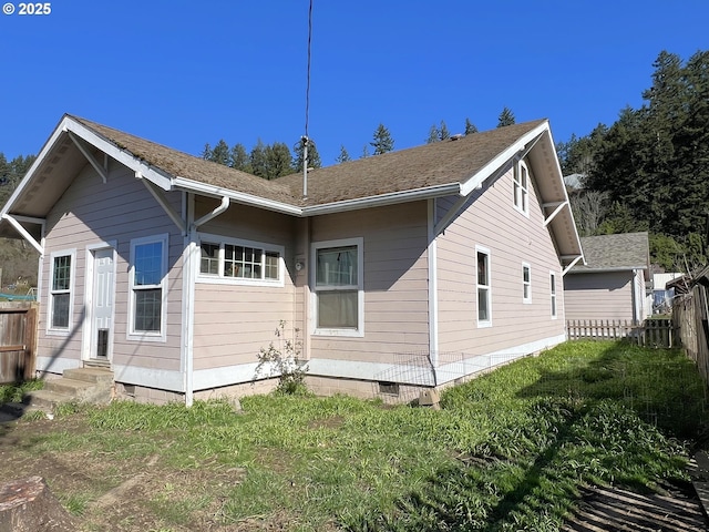 back of property featuring entry steps, a lawn, and fence