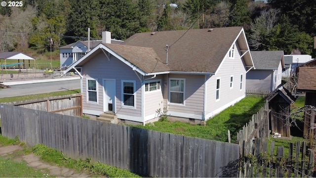 rear view of house with crawl space, a fenced front yard, a chimney, and roof with shingles