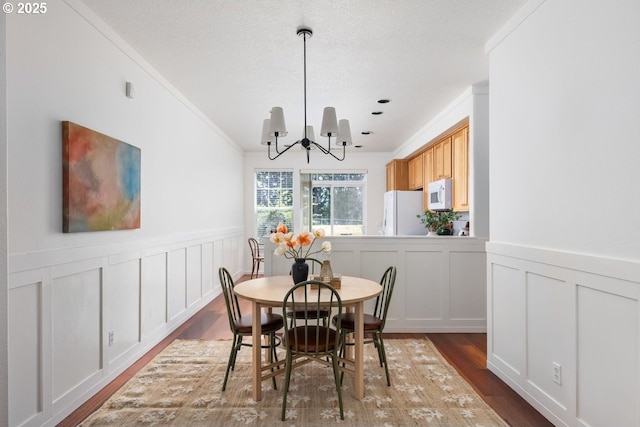 884 NE 73rd Ave, Hillsboro, OR 97124 - dining area featuring ornamental molding, wood finished floors, a decorative wall, a chandelier, and a wainscoted wall