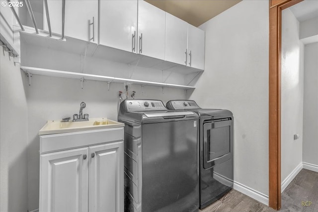 laundry area featuring dark hardwood / wood-style flooring, sink, cabinets, and washing machine and clothes dryer