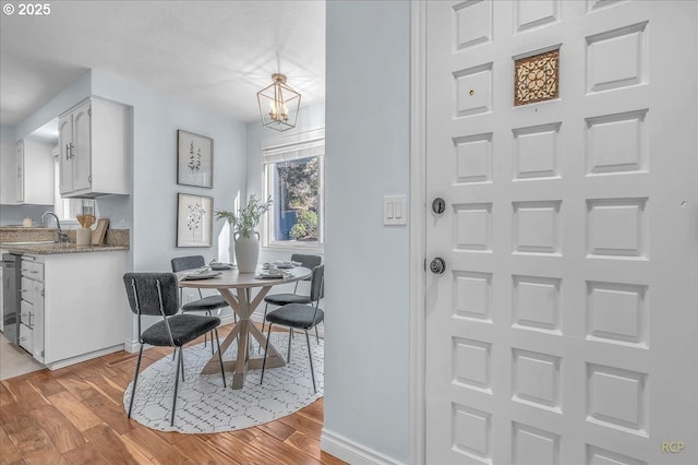 dining space with an inviting chandelier, sink, and light wood-type flooring