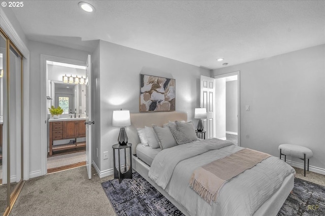 carpeted bedroom featuring sink, ensuite bath, and a textured ceiling