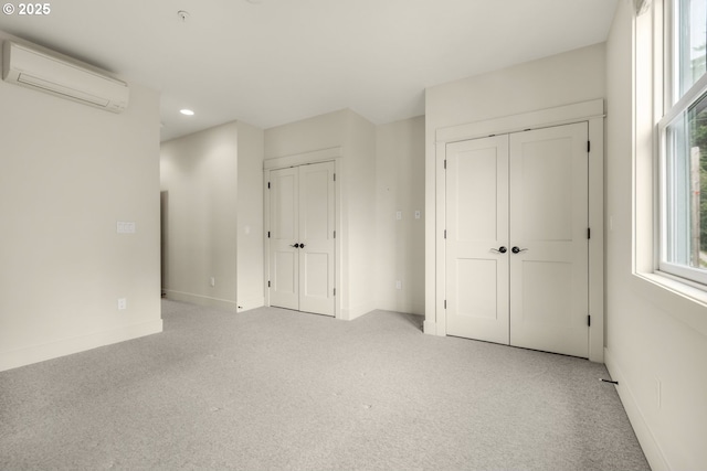unfurnished bedroom with a wall mounted AC, two closets, baseboards, recessed lighting, and carpet