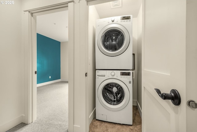 laundry room with stacked washing machine and dryer, carpet, and baseboards