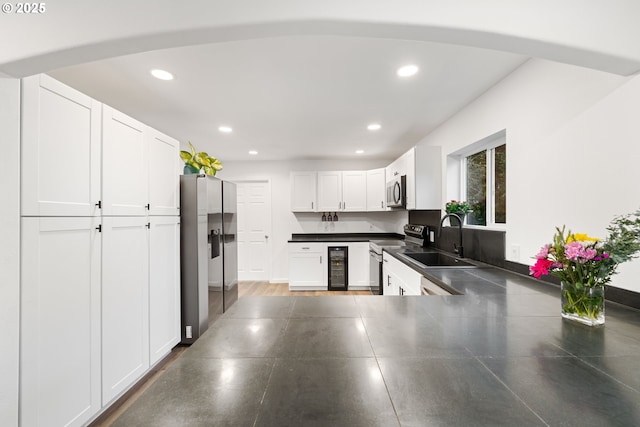 kitchen featuring sink, white cabinetry, stainless steel appliances, wine cooler, and kitchen peninsula