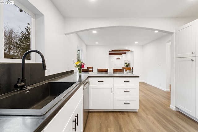 kitchen featuring sink, white cabinets, stainless steel dishwasher, kitchen peninsula, and light wood-type flooring