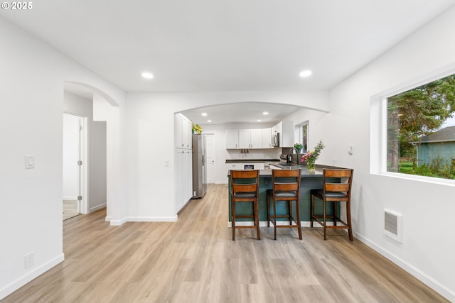 kitchen featuring sink, light hardwood / wood-style flooring, a kitchen breakfast bar, white cabinets, and kitchen peninsula