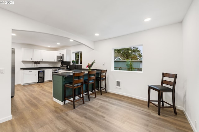 kitchen featuring stainless steel appliances, a kitchen bar, kitchen peninsula, and white cabinets