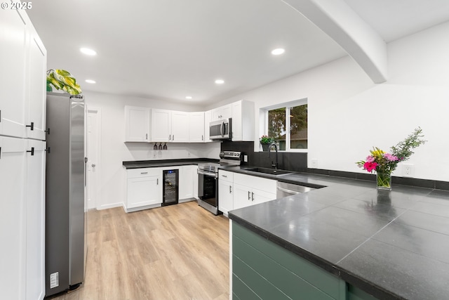 kitchen with sink, white cabinets, wine cooler, kitchen peninsula, and stainless steel appliances