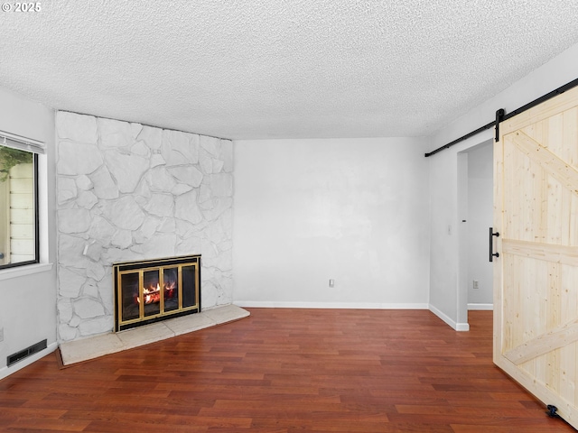3329 NE 162nd Ave, Portland, OR 97230 - unfurnished living room with a barn door, wood finished floors, a textured ceiling, and a fireplace