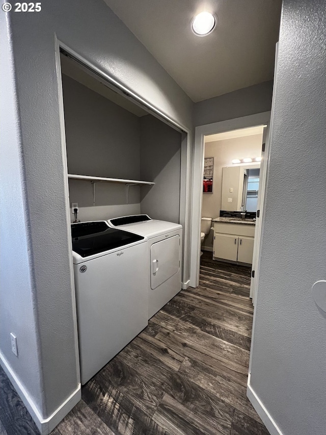 clothes washing area with baseboards, washer and clothes dryer, dark wood finished floors, laundry area, and a textured wall