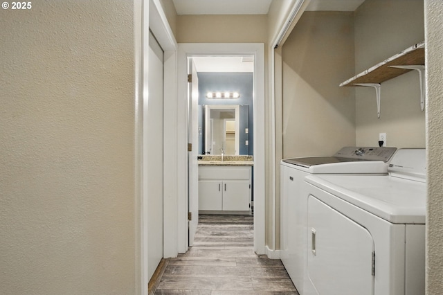 washroom with light wood-style floors, separate washer and dryer, laundry area, and a textured wall