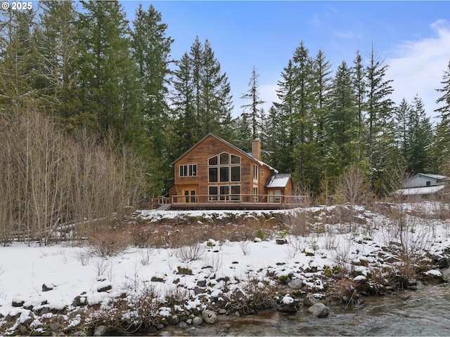 snow covered rear of property with a wooden deck