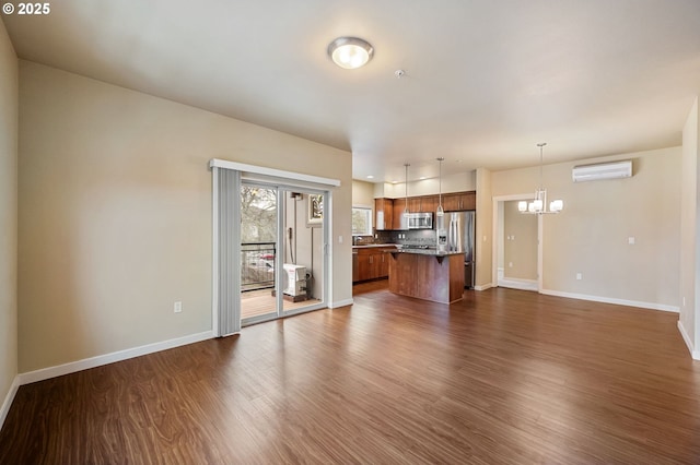 unfurnished living room featuring dark wood-type flooring, a wall unit AC, and a chandelier