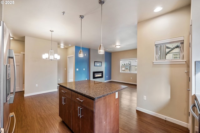 kitchen with a tile fireplace, stainless steel fridge, decorative light fixtures, and dark hardwood / wood-style floors