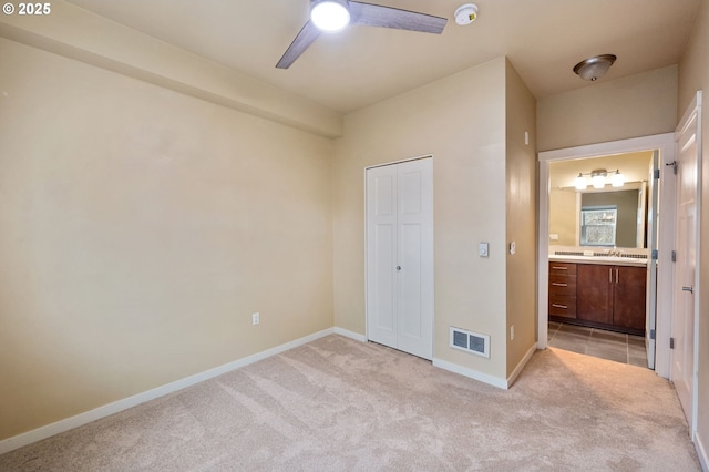 unfurnished bedroom featuring sink, ceiling fan, ensuite bathroom, and light carpet