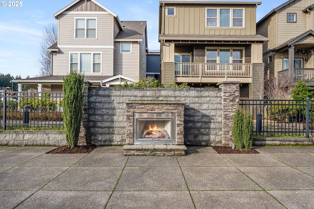 view of front of home with a balcony and an outdoor stone fireplace