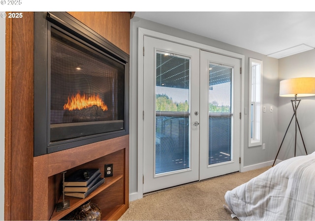 7720 SW Macadam Ave Unit 9, Portland, OR 97219 - bedroom with french doors, access to exterior, carpet, baseboards, and a warm lit fireplace