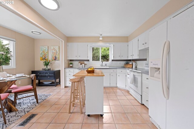 92757 Claremont Rd, Astoria, OR 97103 - kitchen featuring white appliances, a kitchen island, white cabinets, decorative backsplash, and light tile patterned floors