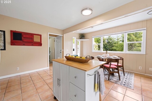 92757 Claremont Rd, Astoria, OR 97103 - kitchen with wooden counters, light tile patterned floors, baseboards, white cabinetry, and a kitchen island