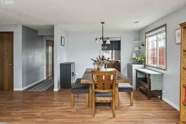 dining room featuring light wood-style floors, a textured ceiling, and baseboards