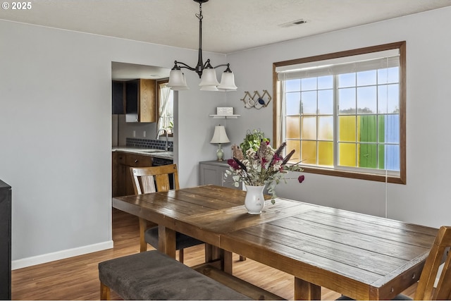 dining room featuring visible vents, baseboards, a wealth of natural light, and wood finished floors