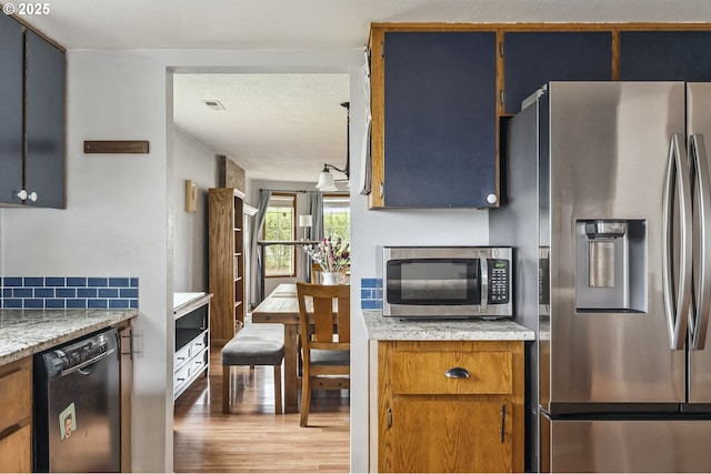 kitchen featuring appliances with stainless steel finishes, light wood-type flooring, visible vents, and light stone countertops