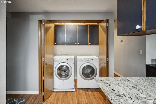 washroom featuring cabinet space, light wood-style flooring, baseboards, and washer and clothes dryer