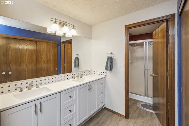 full bath with a textured ceiling, wood finished floors, backsplash, and a sink