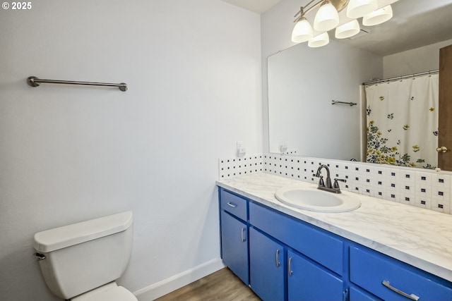 bathroom with baseboards, a shower with shower curtain, toilet, wood finished floors, and vanity