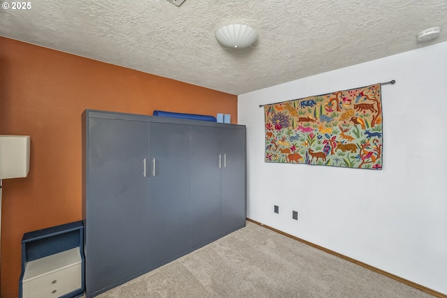 unfurnished bedroom featuring a textured ceiling, a closet, baseboards, and carpet flooring