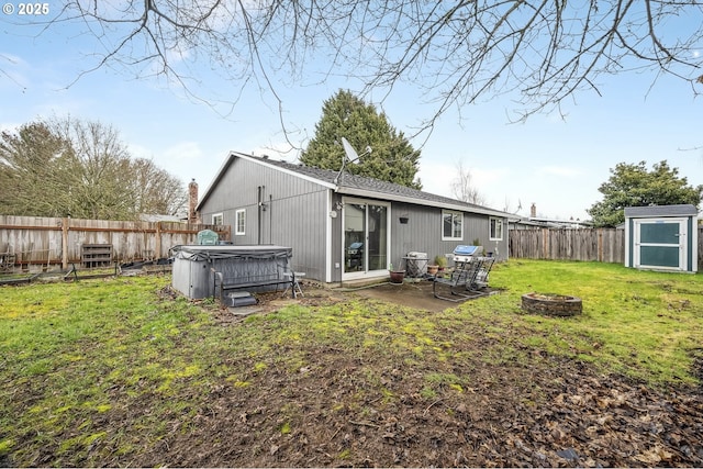 back of property with an outdoor fire pit, a fenced backyard, a yard, and a hot tub