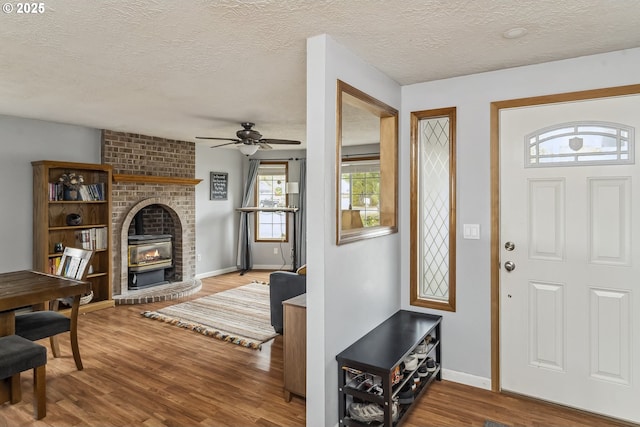 entryway with ceiling fan, a textured ceiling, baseboards, and wood finished floors