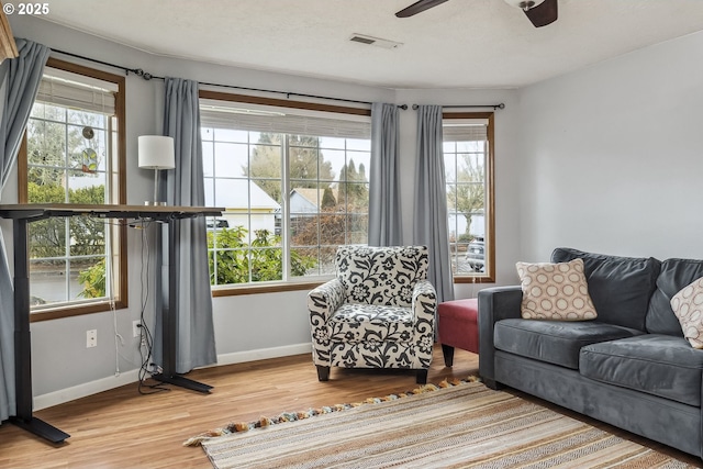 sitting room featuring baseboards, wood finished floors, visible vents, and a healthy amount of sunlight