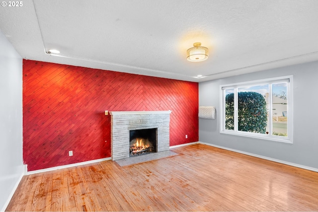 unfurnished living room featuring a fireplace, hardwood / wood-style floors, and a textured ceiling