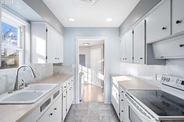 kitchen featuring tasteful backsplash, white range with electric cooktop, sink, and white cabinets