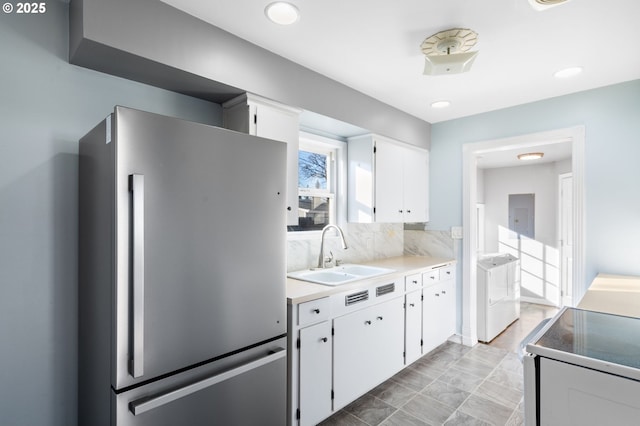 kitchen featuring white cabinetry, sink, electric range oven, and stainless steel refrigerator