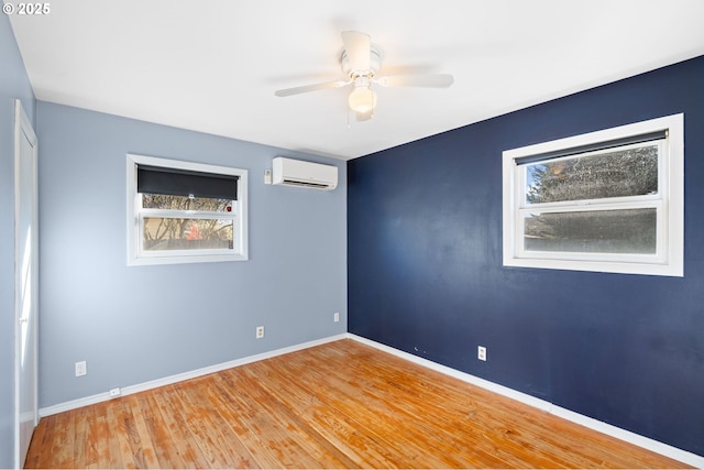 unfurnished room with ceiling fan, wood-type flooring, and a wall mounted AC