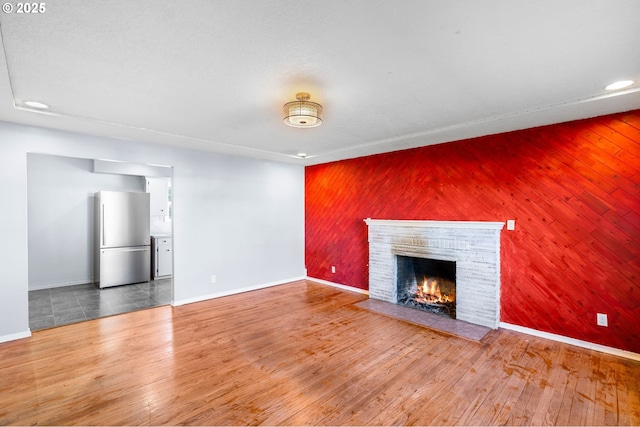 unfurnished living room with wood-type flooring, a fireplace, and wood walls