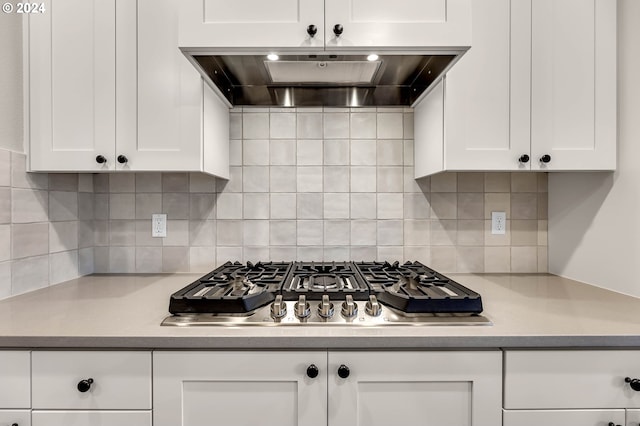 kitchen with stainless steel gas cooktop, tasteful backsplash, ventilation hood, and white cabinets