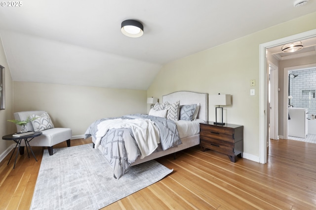 bedroom with wood finished floors, lofted ceiling, and baseboards
