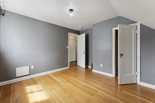 unfurnished room with light wood-style floors, baseboards, and vaulted ceiling
