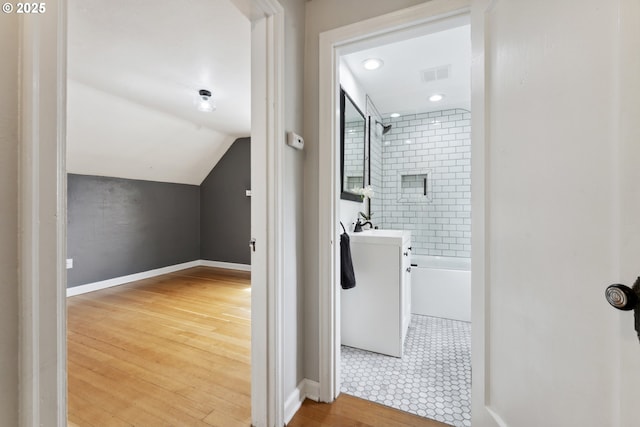 full bathroom with baseboards, bathtub / shower combination, wood finished floors, vaulted ceiling, and vanity
