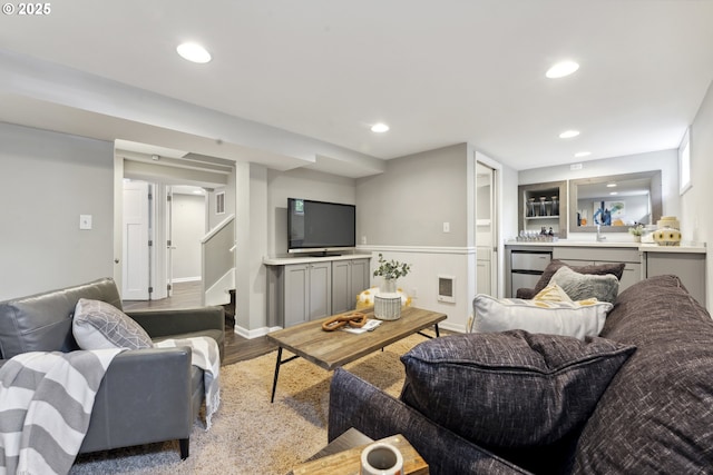living area featuring wood finished floors, a dry bar, a wainscoted wall, recessed lighting, and stairway