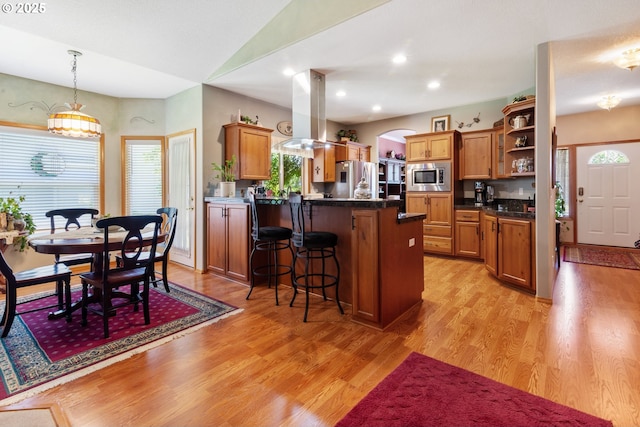 1506 E Heritage Loop, La Center, WA 98629 - kitchen with stainless steel appliances, island exhaust hood, open shelves, a kitchen breakfast bar, and brown cabinets