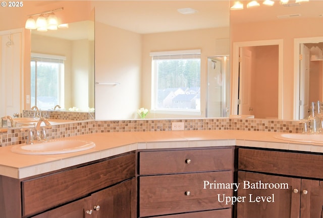 full bathroom featuring a sink, backsplash, and double vanity