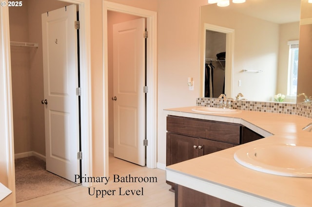 full bath with a sink, double vanity, and a spacious closet