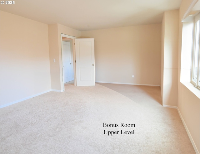 unfurnished room featuring baseboards and light carpet