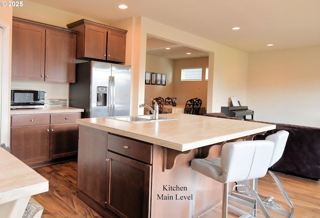 kitchen with dark wood-style floors, a breakfast bar, a sink, stainless steel appliances, and light countertops