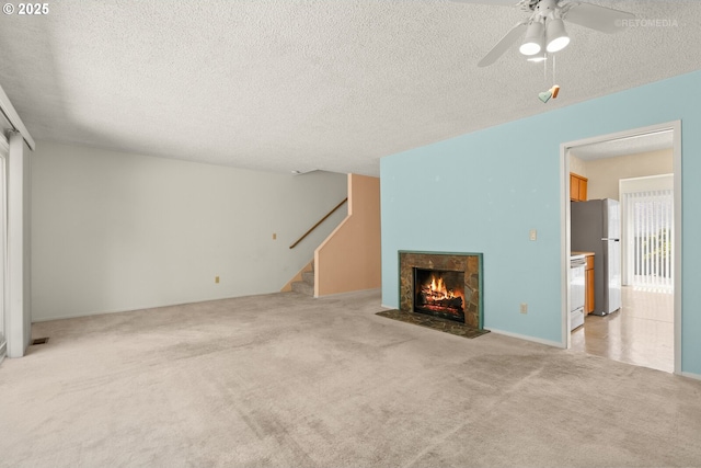 5312 SW Erickson Ave, Beaverton, OR 97005 - unfurnished living room featuring light colored carpet, a textured ceiling, stairs, a fireplace with flush hearth, and ceiling fan